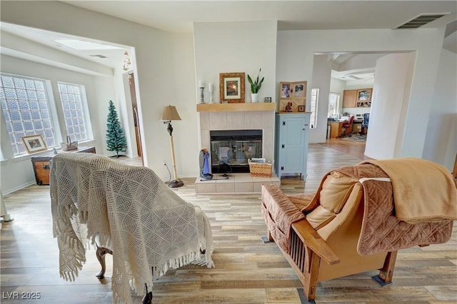 living room with a tiled fireplace and light hardwood / wood-style floors