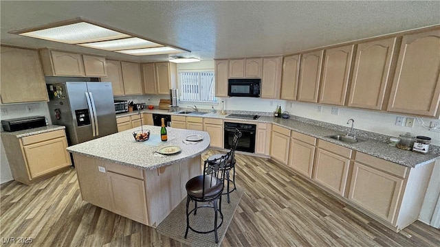 kitchen featuring light brown cabinetry, sink, black appliances, and a kitchen island