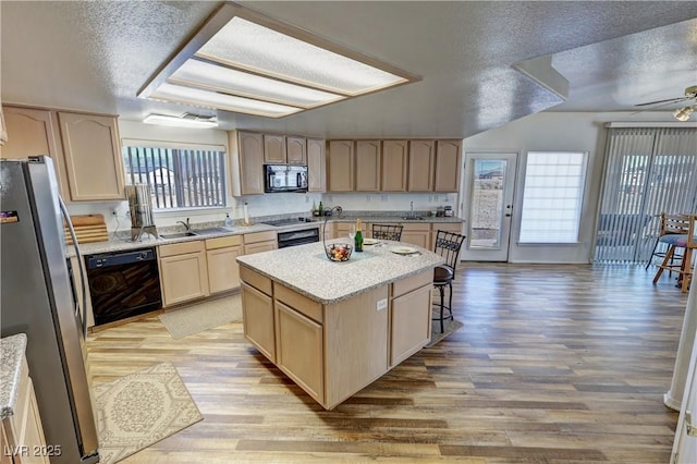 kitchen featuring a kitchen island, light brown cabinetry, sink, black appliances, and a textured ceiling