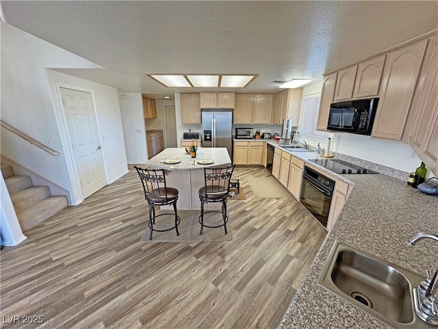 kitchen featuring sink, light hardwood / wood-style flooring, light brown cabinetry, and black appliances