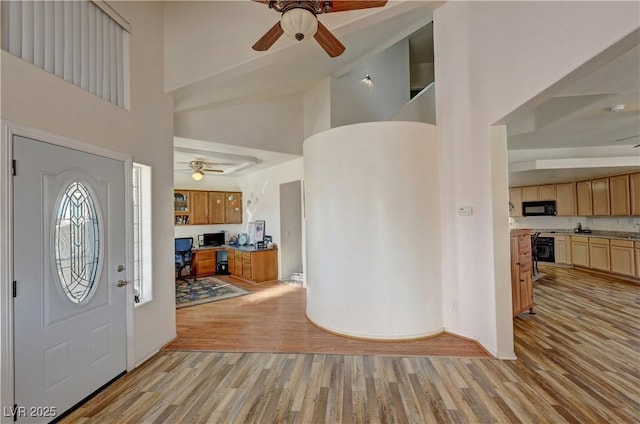 entrance foyer with a towering ceiling, ceiling fan, and light wood-type flooring