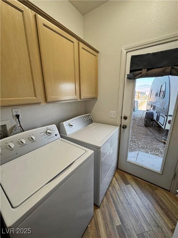 laundry area featuring cabinets, washing machine and clothes dryer, and dark hardwood / wood-style flooring