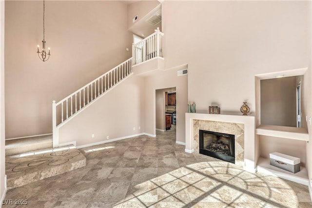 unfurnished living room with a towering ceiling, a fireplace, and a notable chandelier