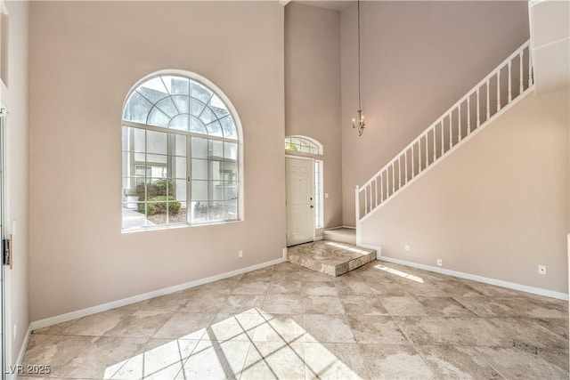 entryway with a towering ceiling, a wealth of natural light, and a notable chandelier