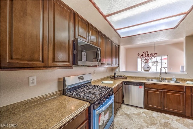 kitchen featuring pendant lighting, sink, light tile patterned floors, appliances with stainless steel finishes, and a textured ceiling