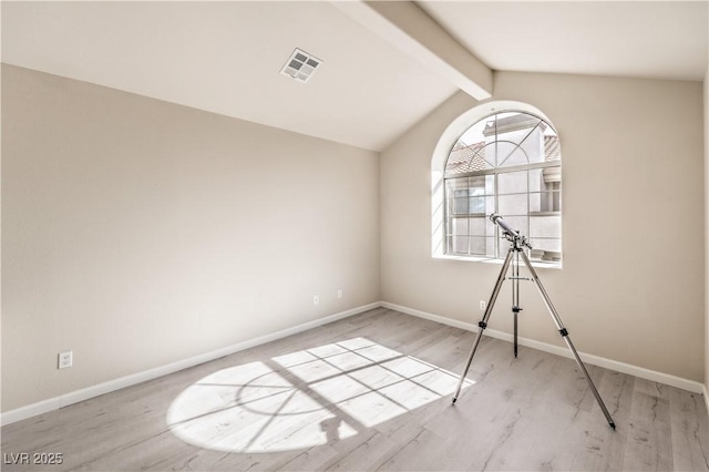 spare room featuring lofted ceiling with beams and light hardwood / wood-style floors