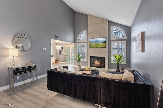 living room with high vaulted ceiling, hardwood / wood-style floors, a notable chandelier, and a fireplace