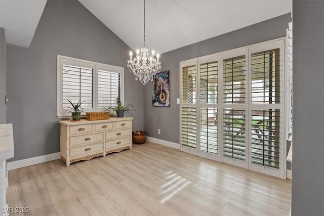 dining room with an inviting chandelier, a wealth of natural light, high vaulted ceiling, and light wood-type flooring