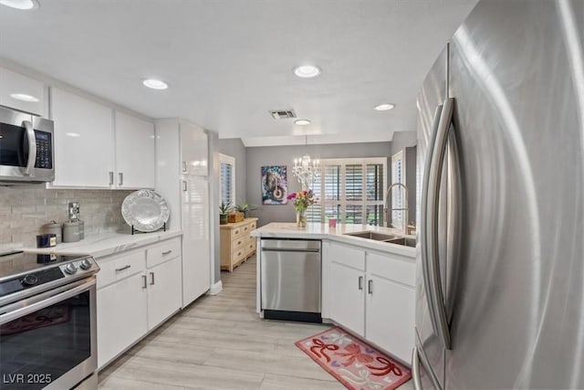 kitchen featuring white cabinetry, stainless steel appliances, sink, and pendant lighting