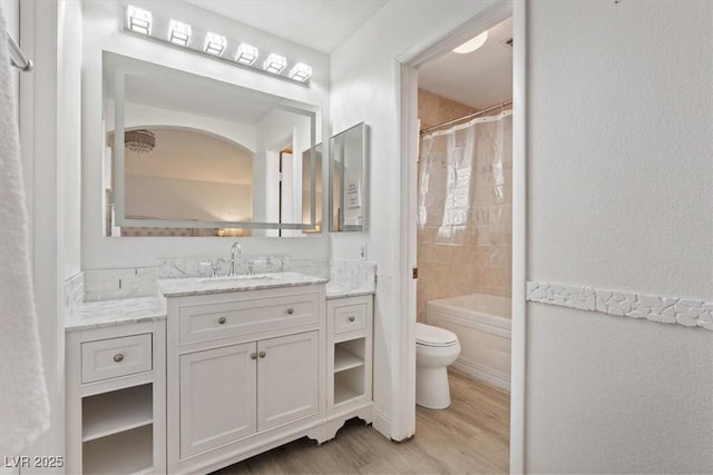 full bathroom featuring hardwood / wood-style flooring, shower / tub combo with curtain, vanity, and toilet