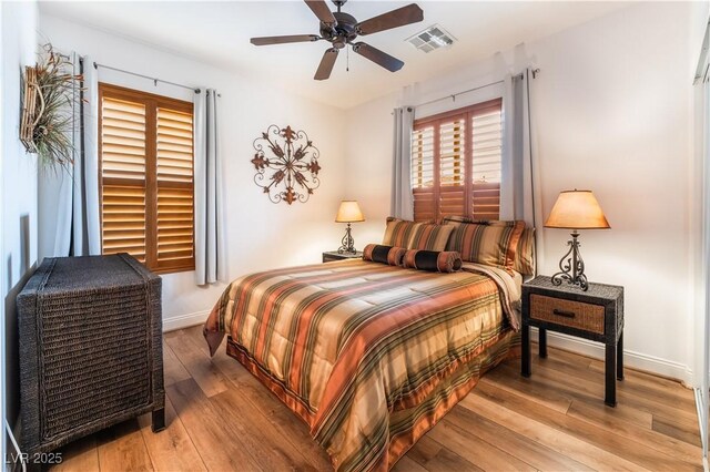 bedroom with light wood-style floors, baseboards, visible vents, and a ceiling fan