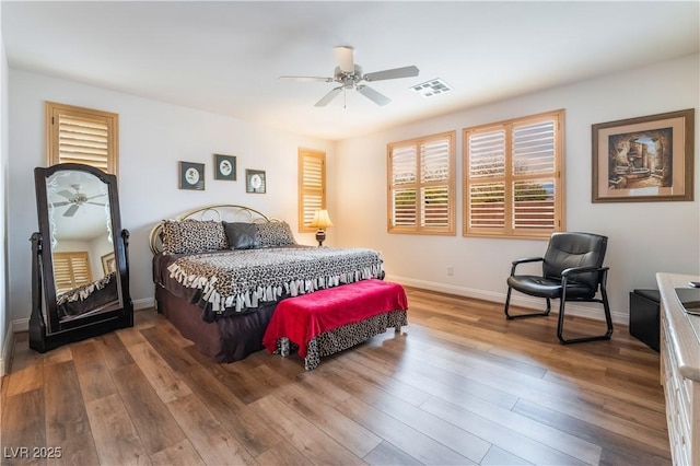 bedroom featuring ceiling fan, wood finished floors, visible vents, and baseboards