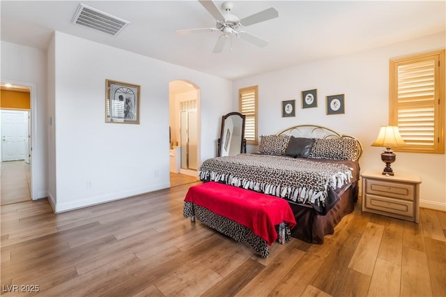 bedroom with baseboards, visible vents, arched walkways, a ceiling fan, and light wood-type flooring