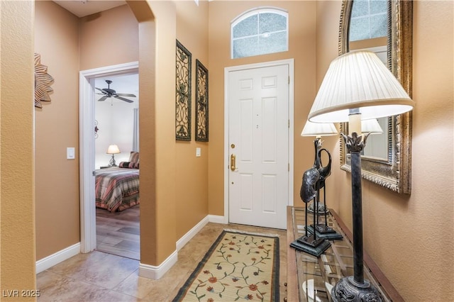 entryway featuring arched walkways, baseboards, and light tile patterned floors