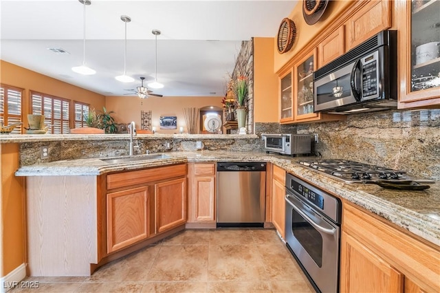 kitchen featuring appliances with stainless steel finishes, a sink, light stone counters, and decorative backsplash