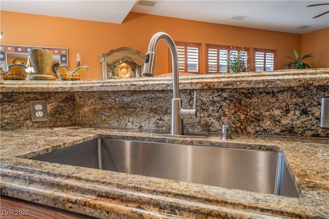 details with a ceiling fan, a sink, and light stone countertops