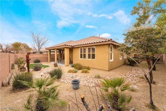 rear view of house featuring a tile roof, a patio area, a fenced backyard, and stucco siding