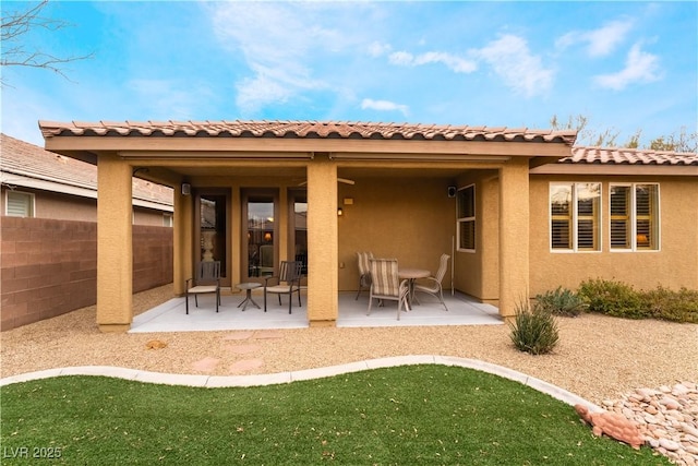 rear view of property featuring a patio, fence, and stucco siding