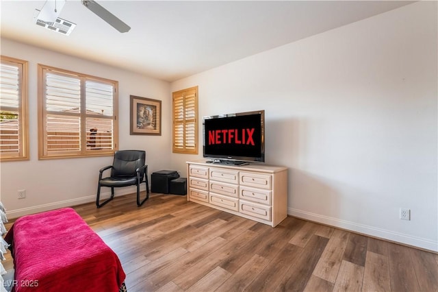 living area with wood finished floors, visible vents, and baseboards