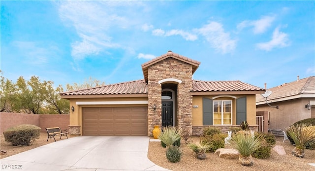 mediterranean / spanish-style home with driveway, stone siding, an attached garage, and stucco siding