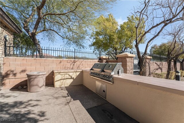 view of patio with exterior kitchen, fence, and grilling area