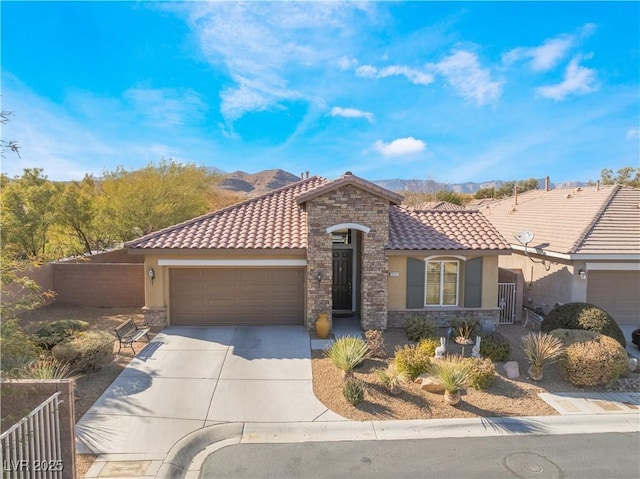 mediterranean / spanish home featuring stone siding, a tile roof, driveway, and stucco siding