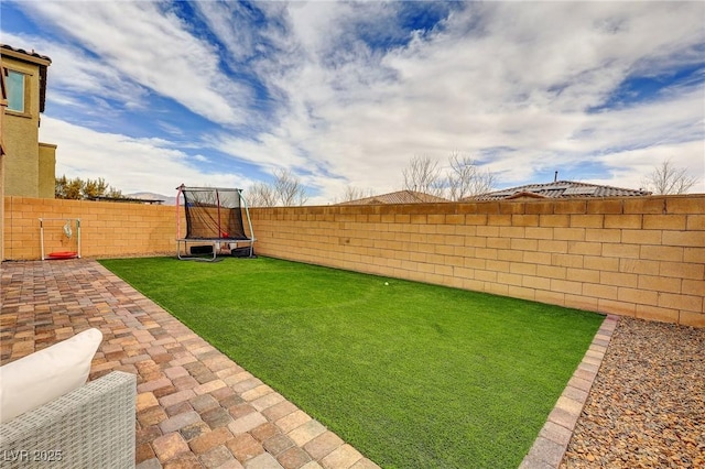 view of yard featuring a trampoline and a patio