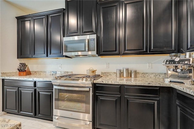 kitchen with stainless steel appliances, light tile patterned flooring, and light stone countertops