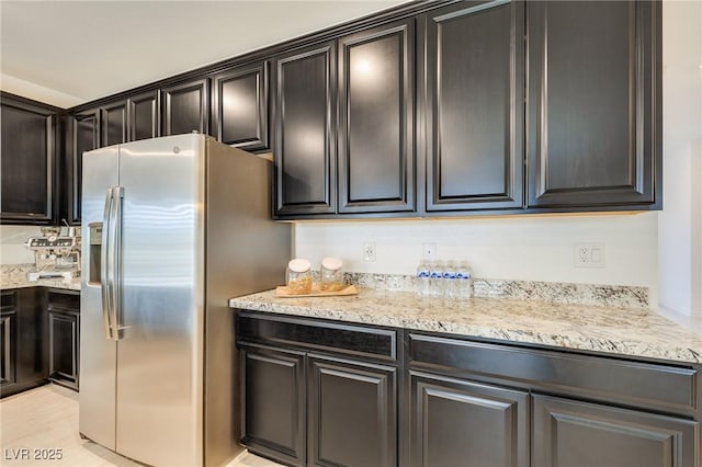 kitchen featuring stainless steel refrigerator with ice dispenser and light stone counters