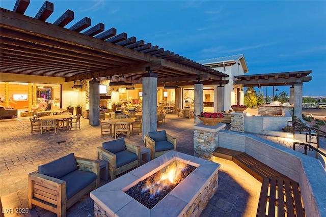 patio terrace at dusk featuring a pergola and an outdoor living space with a fire pit