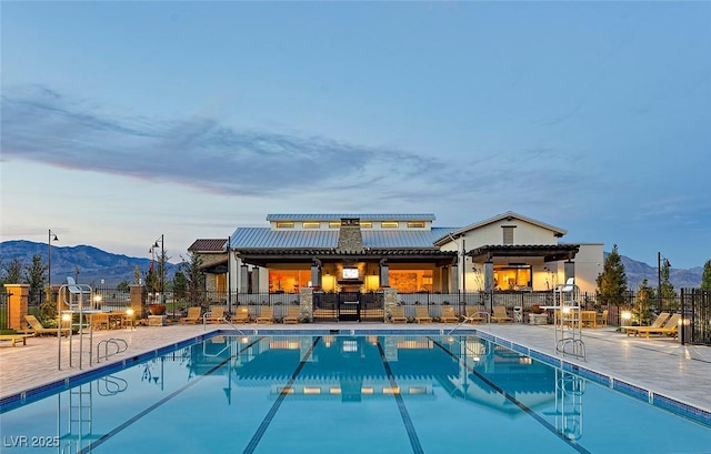 pool at dusk with a mountain view and a patio area