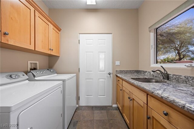 clothes washing area with sink, washer and clothes dryer, cabinets, and a textured ceiling