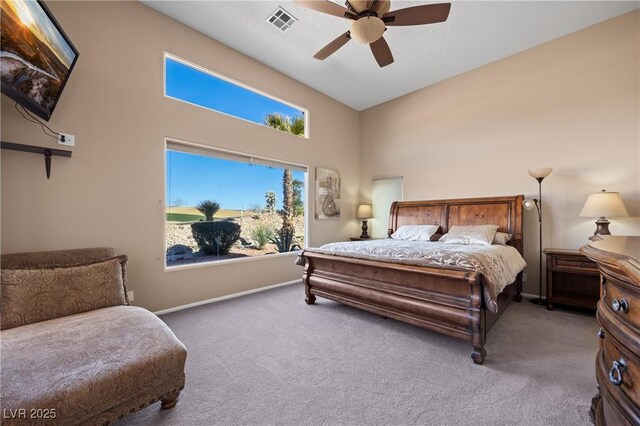 carpeted bedroom with ceiling fan and a high ceiling