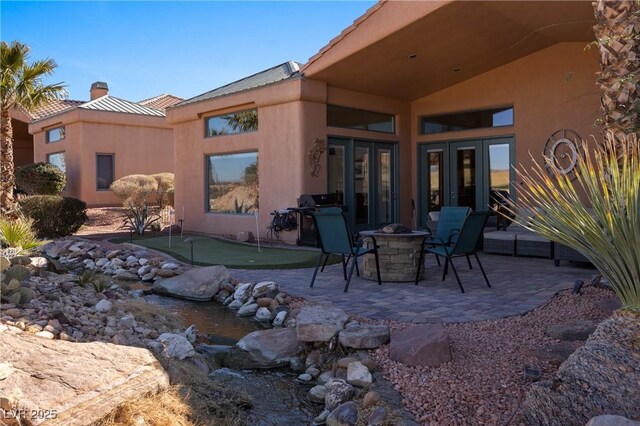 back of property with a patio and an outdoor fire pit