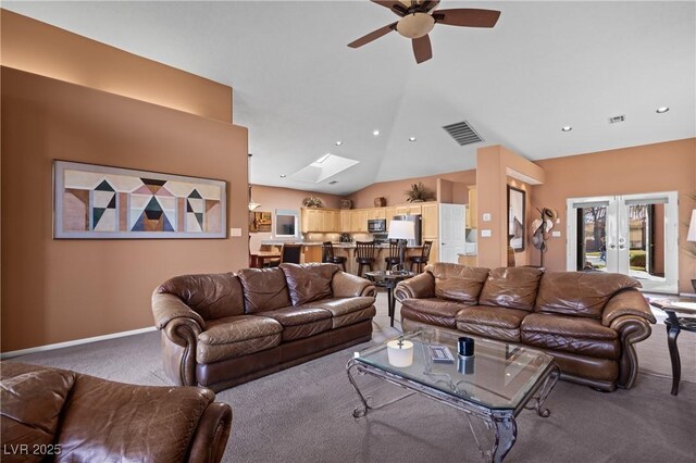 living room featuring french doors, ceiling fan, vaulted ceiling with skylight, and carpet