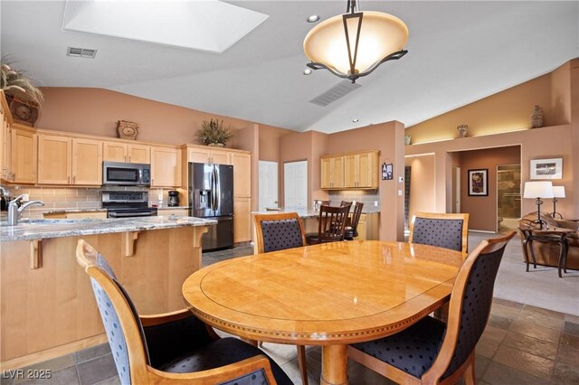 dining room featuring sink and vaulted ceiling with skylight