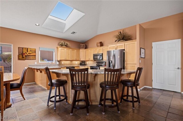 kitchen with decorative backsplash, stainless steel appliances, a kitchen breakfast bar, and light brown cabinets