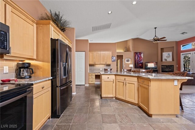 kitchen featuring appliances with stainless steel finishes, a kitchen breakfast bar, a kitchen island, and light brown cabinets