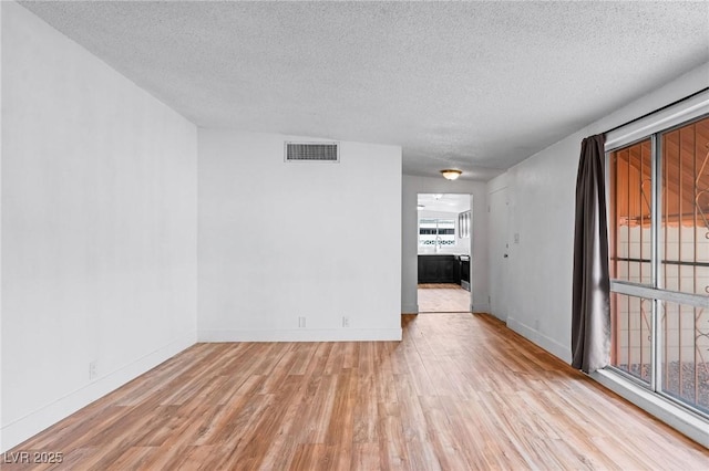 unfurnished room featuring light hardwood / wood-style flooring and a textured ceiling