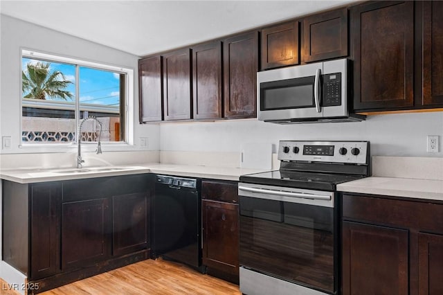 kitchen featuring dark brown cabinetry, appliances with stainless steel finishes, sink, and light hardwood / wood-style flooring