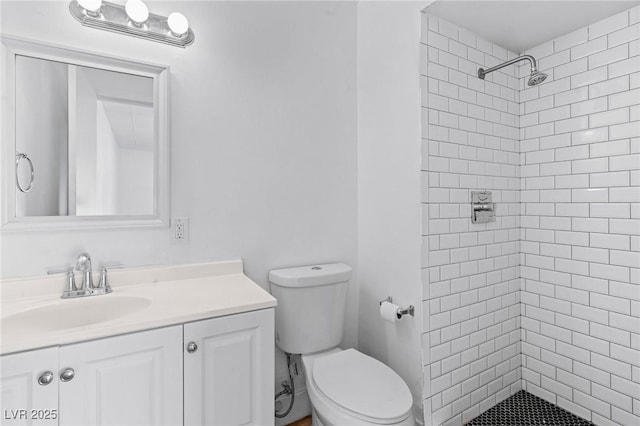 bathroom with vanity, toilet, and a tile shower