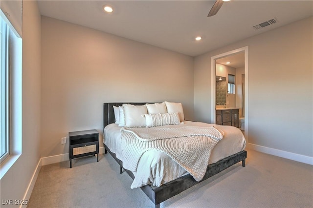 bedroom featuring light carpet, ceiling fan, and ensuite bathroom