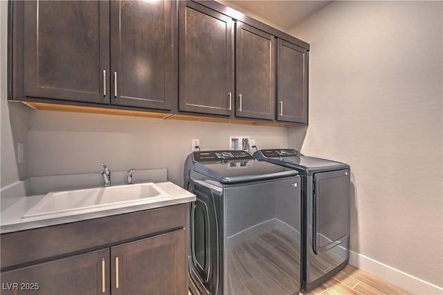 washroom with cabinets, independent washer and dryer, light hardwood / wood-style floors, and sink