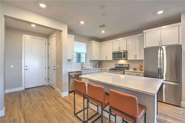 kitchen featuring sink, a kitchen breakfast bar, stainless steel appliances, a center island, and white cabinets