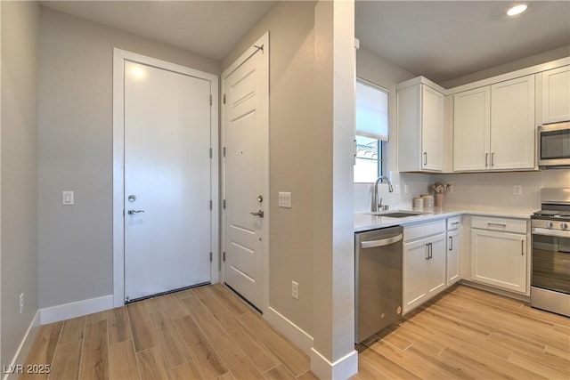 kitchen with stainless steel appliances, light hardwood / wood-style floors, sink, and white cabinets