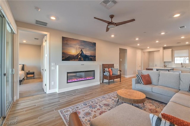 living room with ceiling fan, light hardwood / wood-style floors, and sink