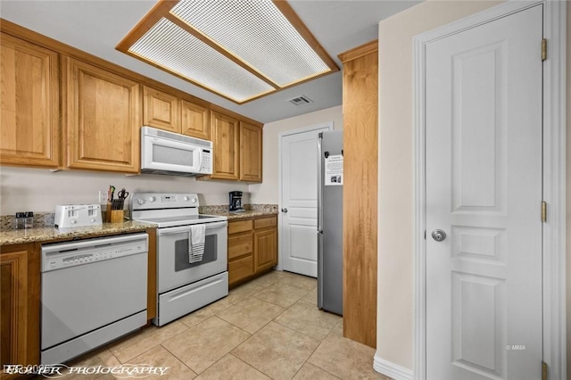 kitchen with light stone counters, white appliances, and light tile patterned flooring