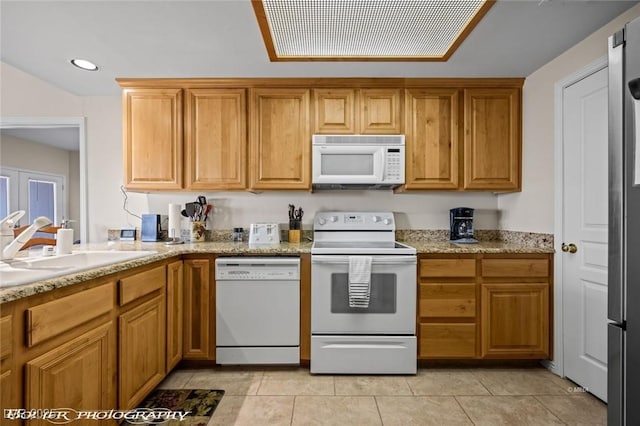 kitchen featuring light stone counters, sink, white appliances, and light tile patterned floors