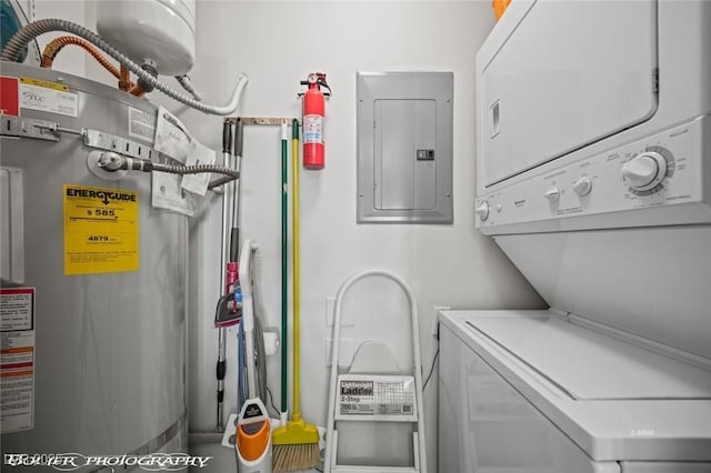 laundry area with stacked washer and clothes dryer, electric panel, and water heater