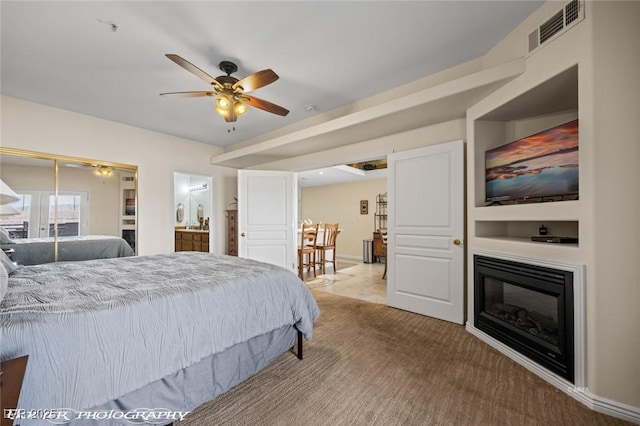 carpeted bedroom with ensuite bath, a closet, and ceiling fan